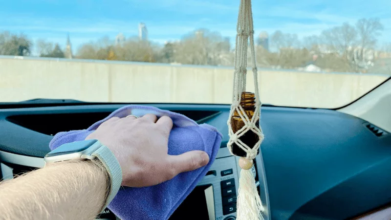 Hand cleaning around membrane keypad in car.