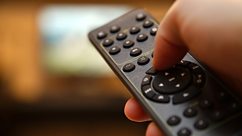 A man is pressing the remote control keypad.