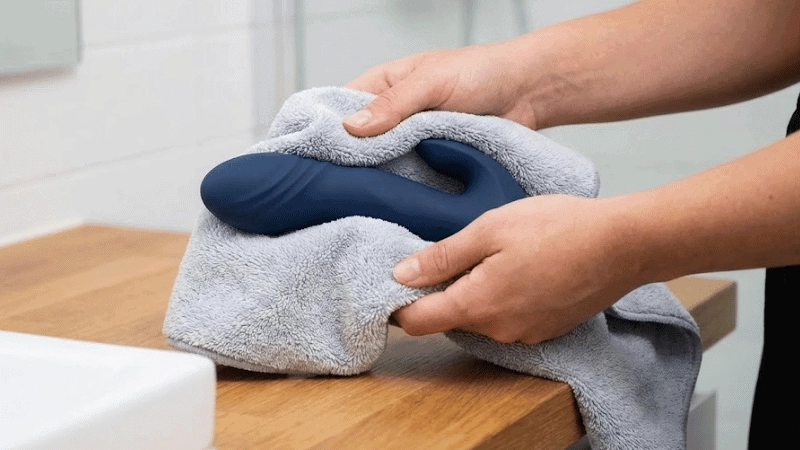 A woman is drying a sex silicone toy with a towel.