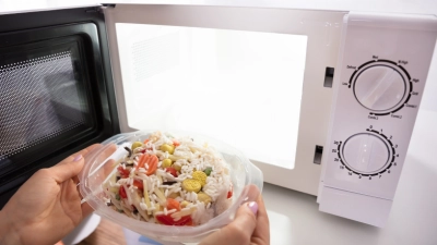 Eine Frau stellt eine Silikonschüssel mit Essen in die Mikrowelle.